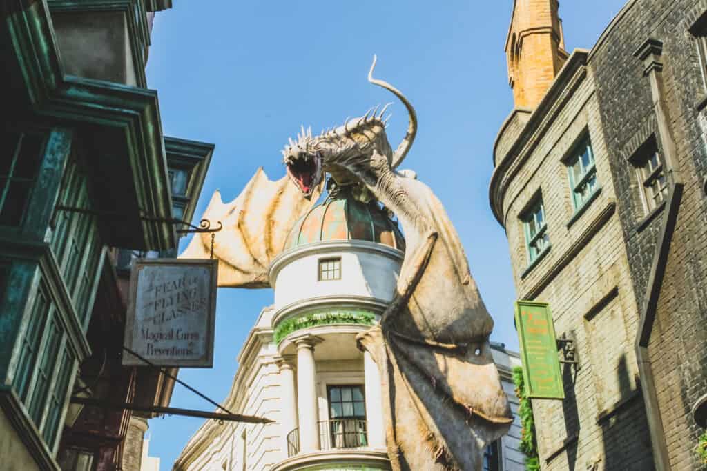 Dragon on top of Gringotts Bank in between storefronts in front of blue skies at Harry Potter World Orlando. The dragon is a must see on any 2 day Harry Potter World Itinerary