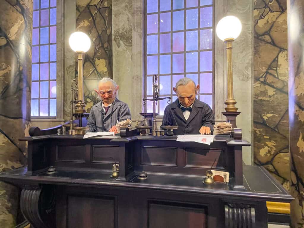two animatronic goblins at a desk. This is in the queue for Escape from Gringotts ride at Harry Potter World Diagon Alley