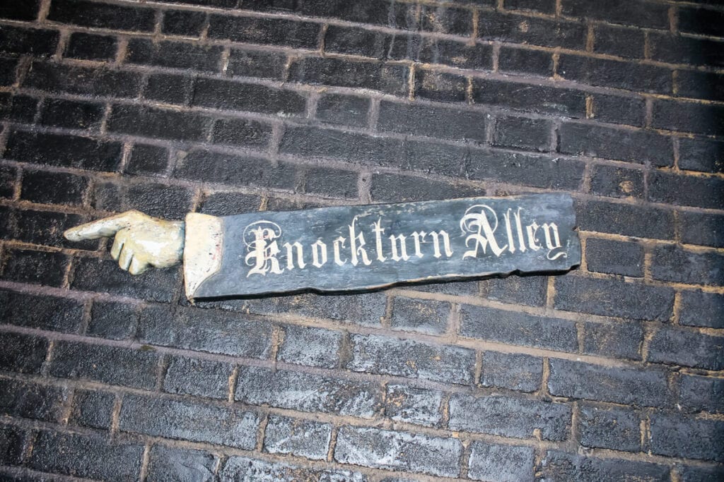 wooden Knockturn Alley sign on black brick wall in Diagon Alley