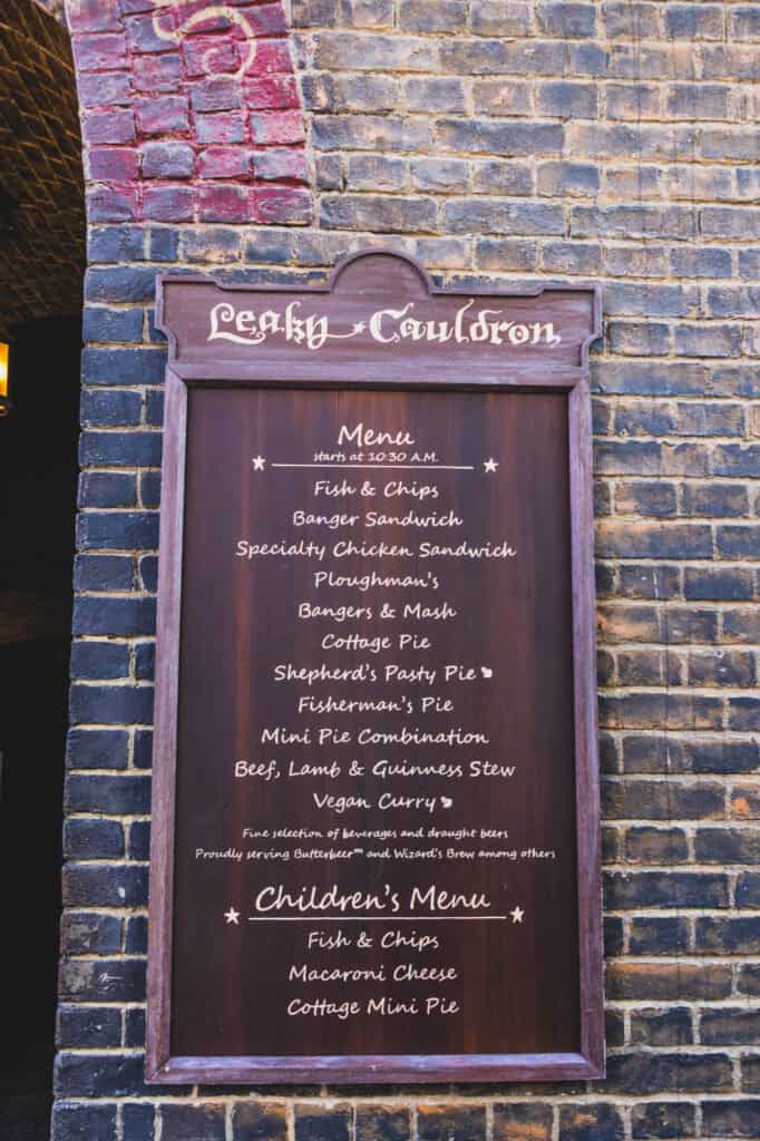 A close-up of the Leaky Cauldron menu in Diagon Alley at Universal Studios Florida shows traditional British pub fare like fish & chips, shepherd’s pie, and bangers & mash. This cozy dining spot is a flavorful stop to include in your Harry Potter World itinerary.
