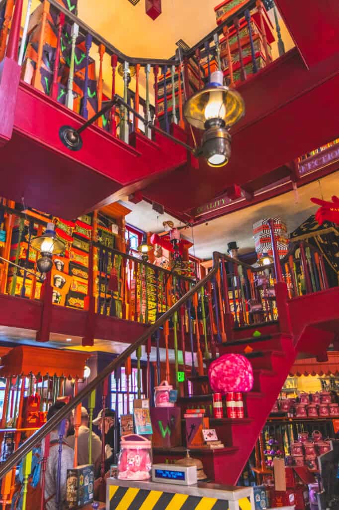The whimsical interior of Weasleys' Wizard Wheezes in Diagon Alley overflows with bright colors, magical prank products, and stacked boxes across multiple staircases and levels. This lively joke shop is a vibrant and quirky stop in Harry Potter World that captures the playful spirit of the Weasley twins.