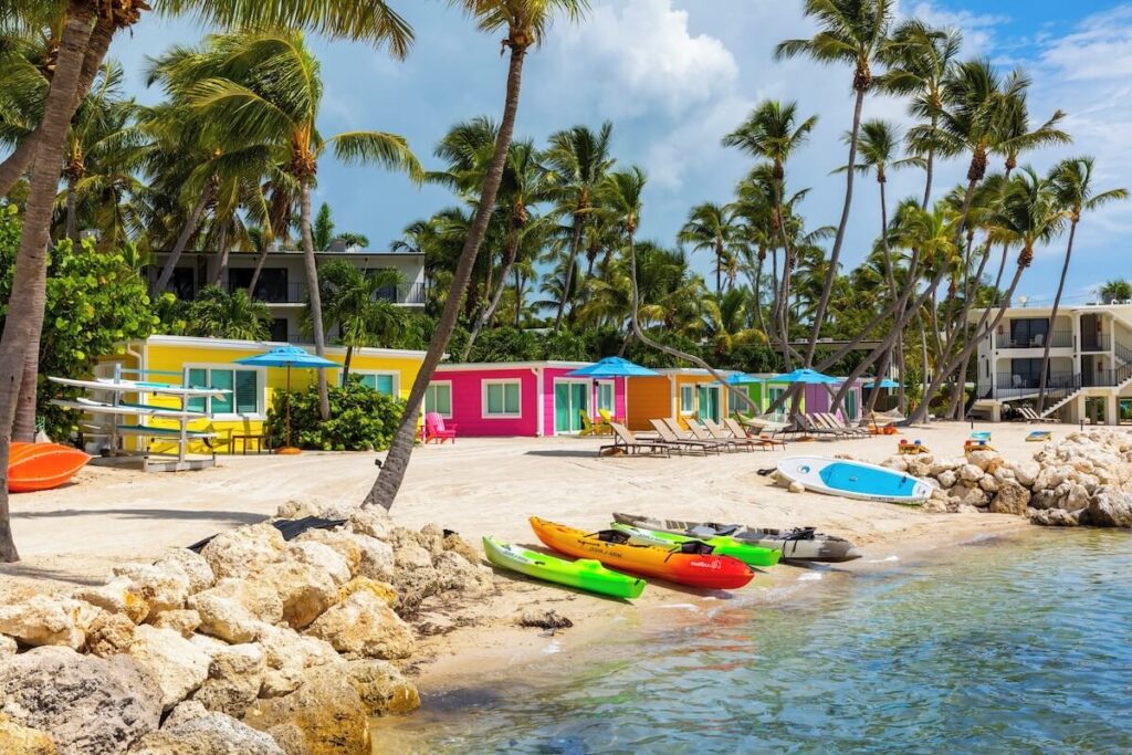 multi-colored kayaks on a beach with colorful casitas in the background at La Siesta Resort in Islamorada, florida