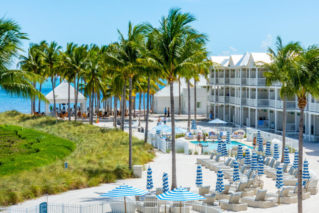 palm trees, beach chairs, and a pool in the distance in front of a white resort. Taken at Isla Bella Beach Resort in the Florida Keys.