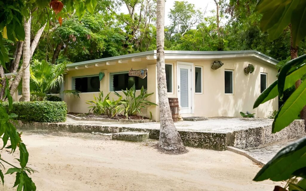 light yellow bungalow with sand and palm trees around it at the Largo Resort in Key Largo, Florida