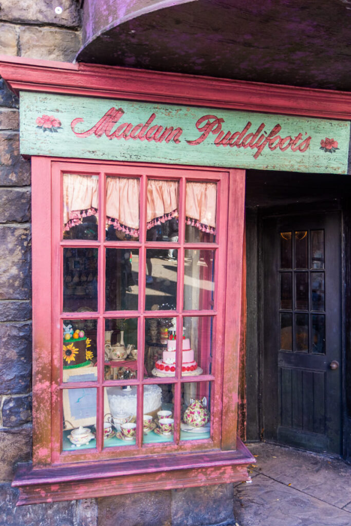 pink window storefront in Hogsmeade Village, with teal and pink sign above reading Madam Puddifoot's