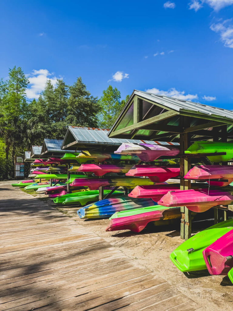 Colorful rental kayaks stacked on covered racks along the boardwalk at Wekiva Island