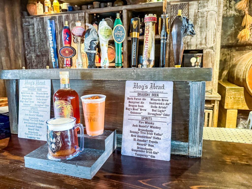 inside of the Hog's Head bar in Islands of Adventure. Countertop with menus, fake drinks, and beer taps in the background